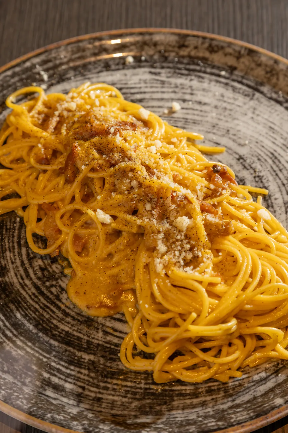 Un piatto di spaghetti con una granella dorata sopra