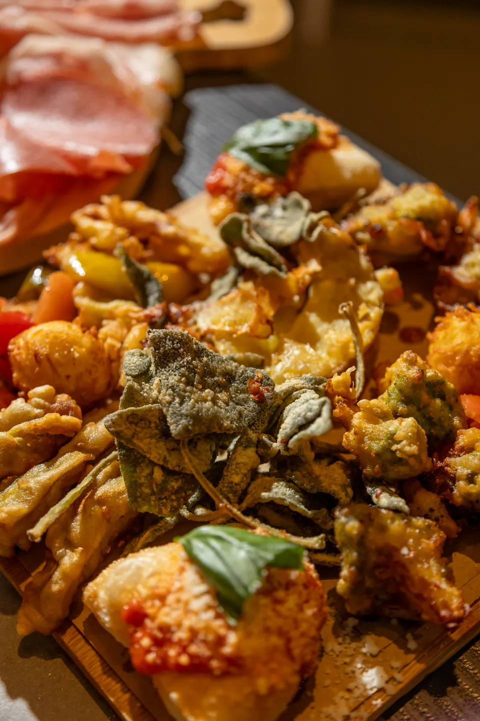 Fritti misti con salvia fritta e basilico su un tagliere di legno